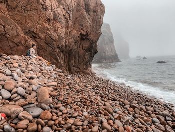 Rock formation on beach against sky