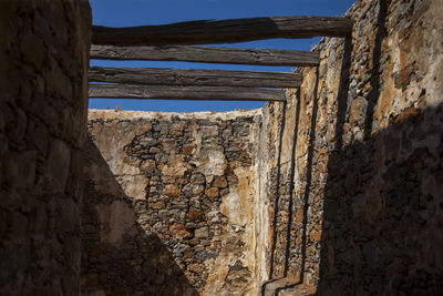 Old wall by sea against sky