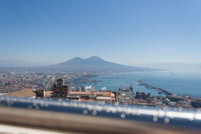 View of buildings by sea against clear blue sky