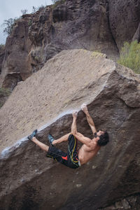 Midsection of man with arms outstretched on rock