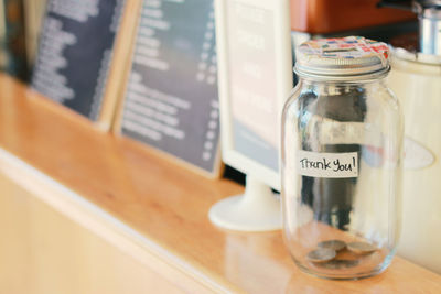 Close-up of coins in glass jar on table at restaurant