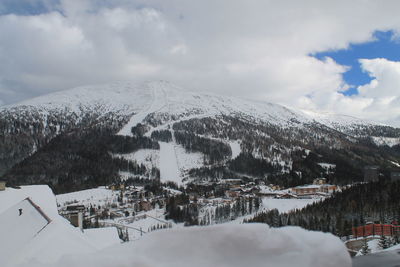 Scenic view of snow covered mountains against cloudy sky