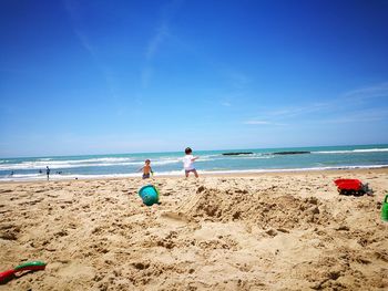 People on beach against blue sky
