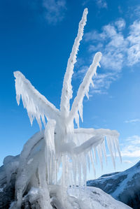 Icicles on snow covered landscape against blue sky