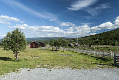 Trees and houses on field against sky