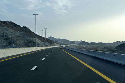 Empty road by mountain against sky