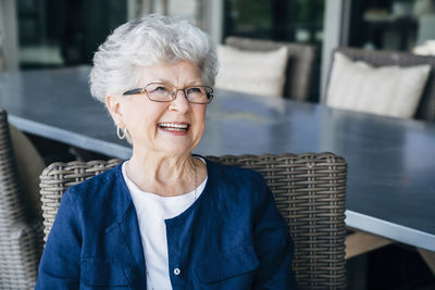 Happy senior woman looking away while sitting on porch