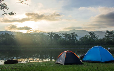 Tent on field by lake against sky