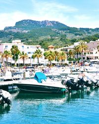 Boats moored at harbor by sea against sky