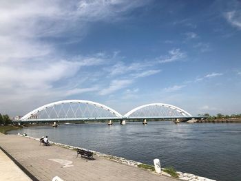 Bridge over river in city against sky