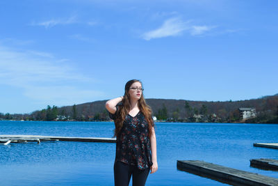 Woman standing by blue river against sky