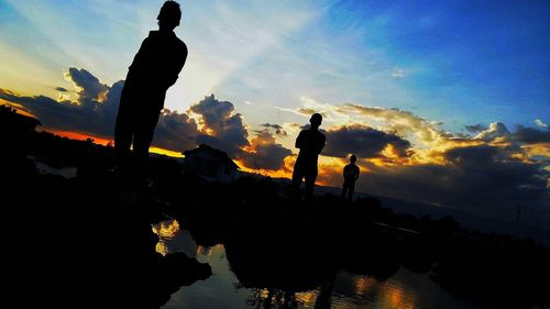 Silhouette men on mountain against sky during sunset