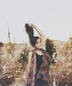 Portrait of smiling young woman standing against clear sky