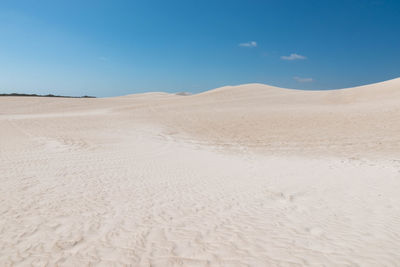 Sand dunes in desert against blue sky