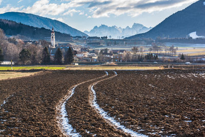 Dirt road in town against mountains