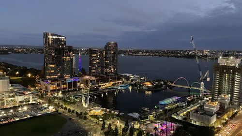 High angle view of illuminated city by river against sky