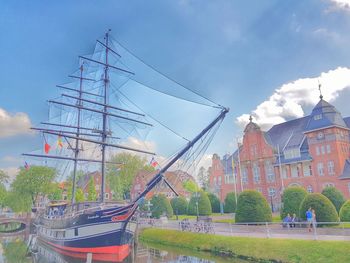 Sailboats moored by buildings in city against sky