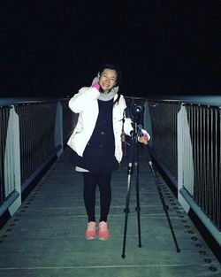 Full length portrait of woman standing against railing