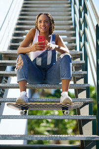 Portrait of young woman sitting on railing