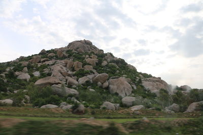 View of rocks on mountain against cloudy sky