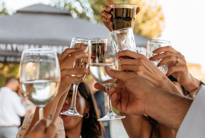 Close-up photo of group of friends clinking glasses, drinking and celebrating