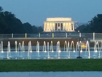 Built structure against clear sky with water in foreground