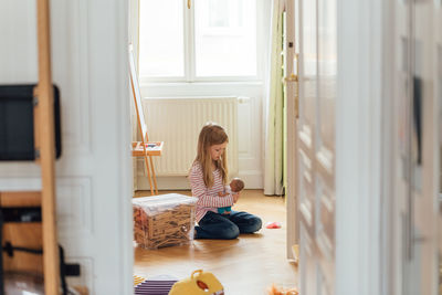 Side view of girl sitting on floor at home