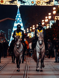 Full length of people on illuminated street at night