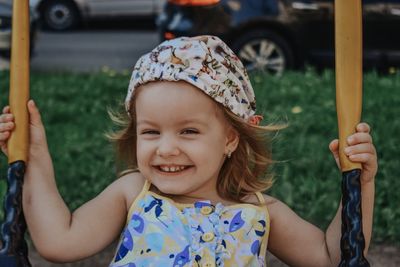 Portrait of cute girl smiling while sitting on swing in park