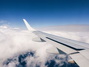 View of airplane wing against cloudy sky