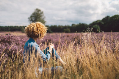 Rear view of woman standing amidst wheat field against sky