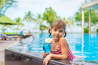 Girl with drinking glass in pool