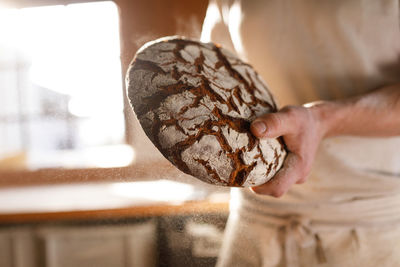 Baker holding round bread in back-lit 