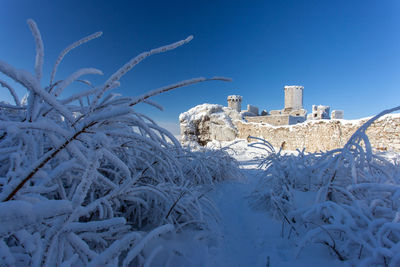 Low angle view of snow covered land against clear blue sky