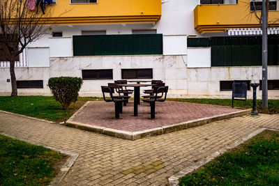 Empty bench in park against building
