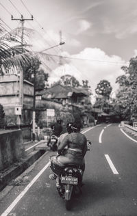 Rear view of man riding motorcycle on road