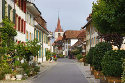 Street amidst trees and buildings against sky