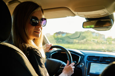 Woman wearing sunglasses is driving car