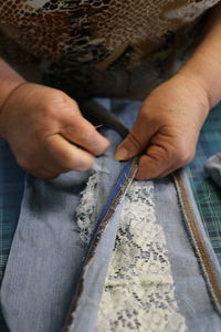 Midsection of tailor sewing lace on jeans