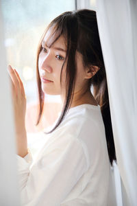 Close-up of young woman standing by window