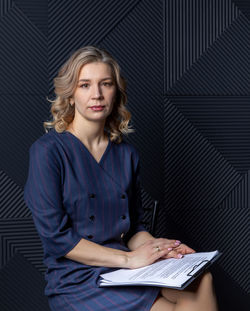 Portrait of a successful female psychologist in her office, notebook in hand.