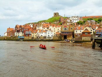 High angle view of men rowing over sea by buildings