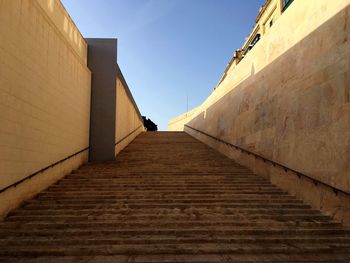 Low angle view of steps amidst buildings against blue sky