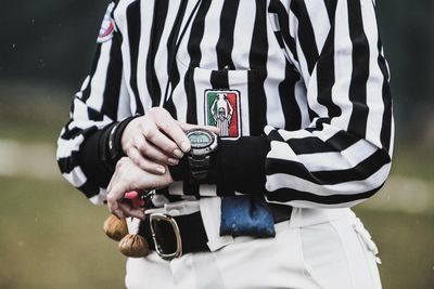 Midsection of man holding camera while standing outdoors