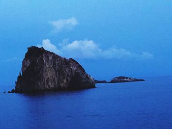 Rock formations in sea against blue sky