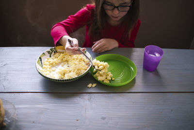 High angle view of girl eating scrambled eggs at table