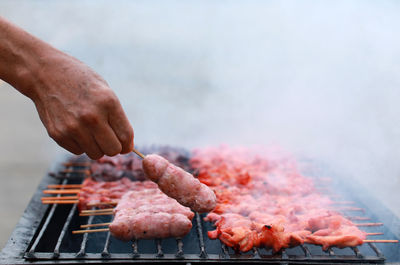 Cropped image of person preparing meat on barbecue grill