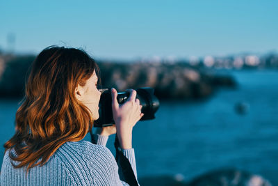 Midsection of woman photographing sea