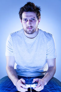 Portrait of man sitting against gray background