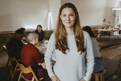Portrait of confident businesswoman with colleagues in background at startup company